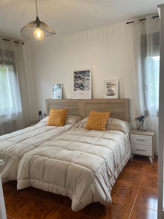 a large bed in a white bedroom with yellow pillows at Balcón da Ría 
