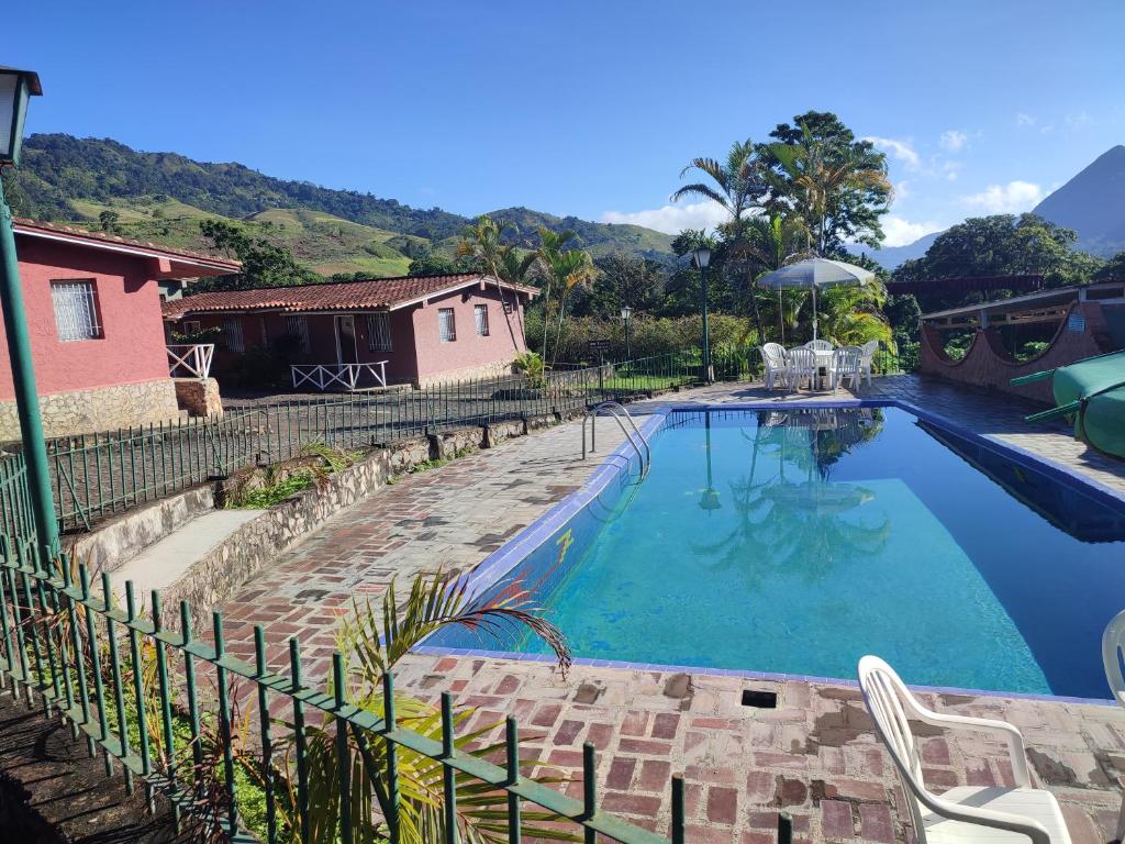 ein Schwimmbad neben einem Haus mit einem Zaun in der Unterkunft Pueblo Pequeño 