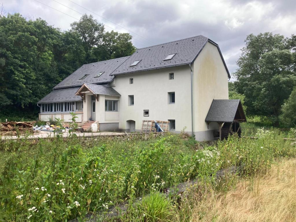 a white barn with a black roof in a field at Mezriczky Malom Kapolcs in Kapolcs