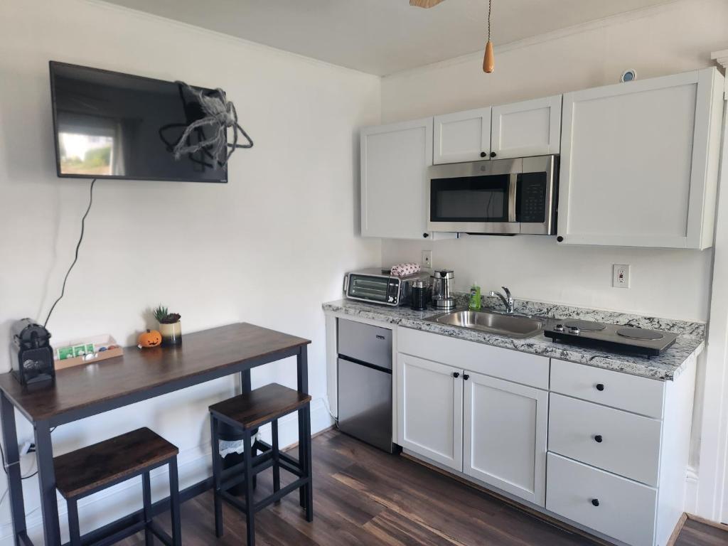 a kitchen with white cabinets and a wooden table at Street side studio apartment in Manchester