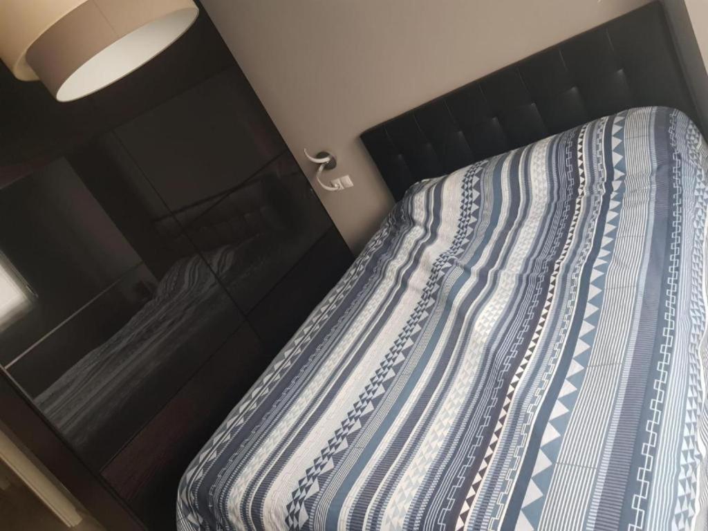 a bed with a blue and white striped comforter at Habitaciones en Ronda in Castro-Urdiales