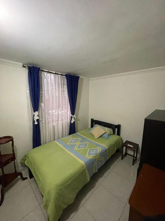 a bedroom with a bed and a window with blue curtains at Linda habitación buena ubicación in Bogotá