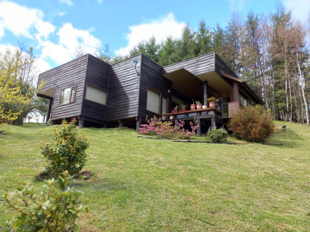 a house on top of a grassy field at Casa Pucon sector Laguna ancapulli in Pucón