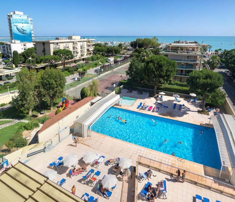 - une vue sur la piscine avec des chaises et des personnes dans l'établissement Grand studio avec terrasse 1min de la mer aux portes de Nice, à Saint-Laurent-du-Var