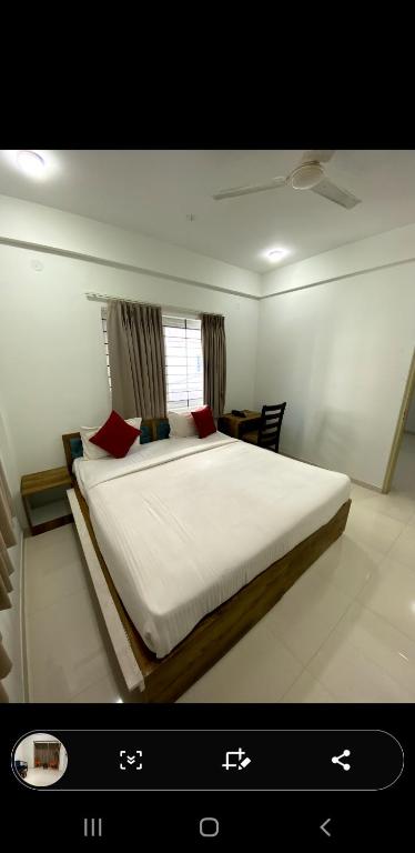 a bedroom with a large bed with white sheets and red pillows at IRIS Manyata in Bangalore