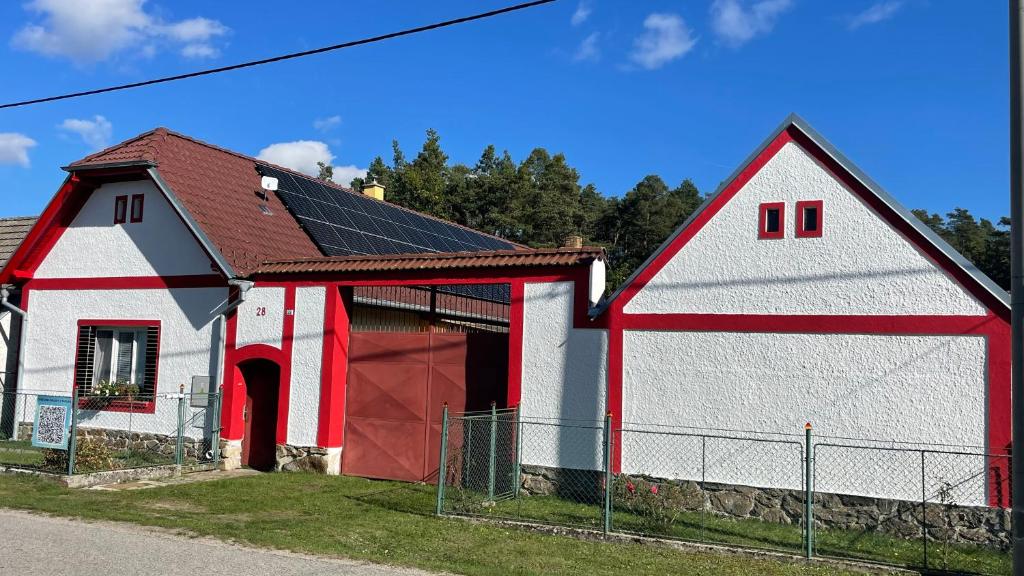 un granero rojo y blanco con una puerta roja en Farmhouse Faflik - Tell the Story - Retro, en Vlkov