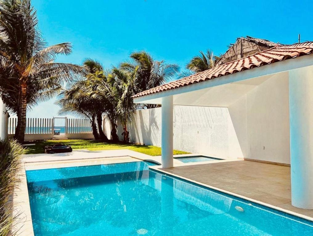 a swimming pool next to a house with palm trees at Casa Trébol: Tu Casa de Playa. Disfruta en familia in Puerto Arista