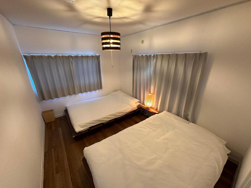 a small room with two beds and a window at Shirako House in Shirako