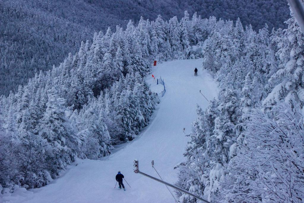 un grupo de personas esquiando por una pista cubierta de nieve en Smugglers' Notch Resort Private Suites, en Cambridge