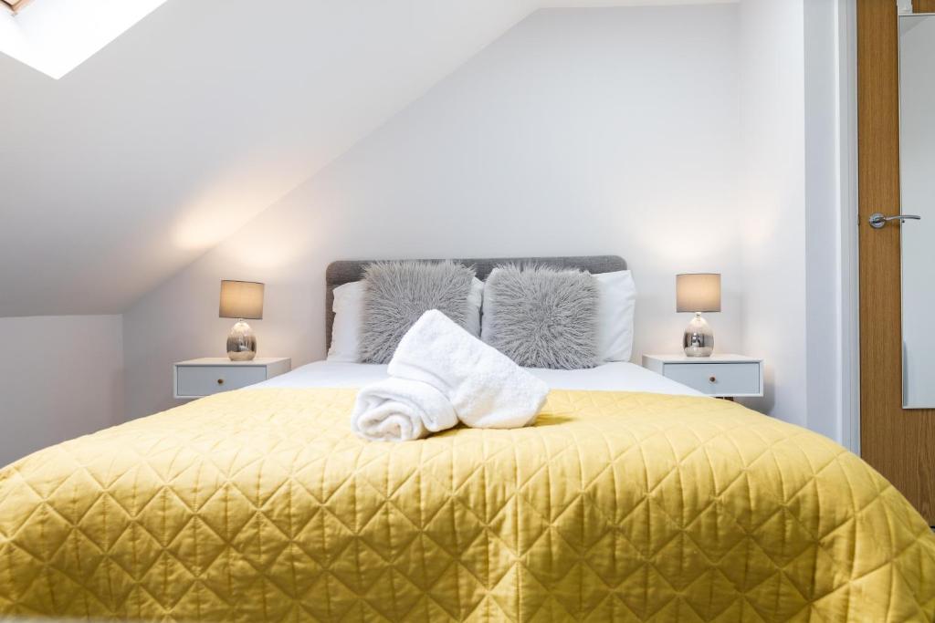 a bedroom with a yellow bed with towels on it at Modern Apartments Near Cardiff City Centre in Cardiff