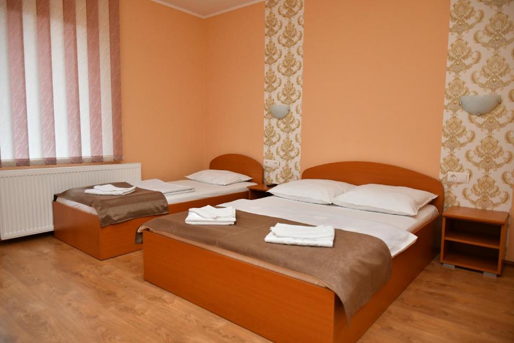 two beds in a room with orange walls at Kelemen Vendégház 2 in Praid