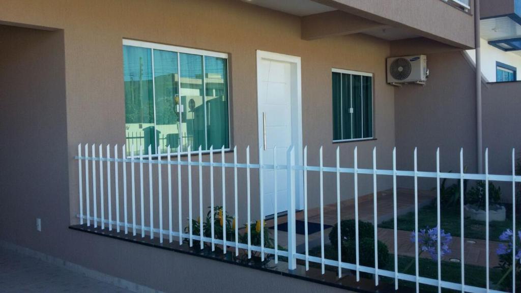 ein weißer Zaun vor einem Haus in der Unterkunft Casa Bombinhas temporada in Bombinhas