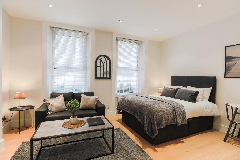 a bedroom with a bed and a couch and a table at Olympic Park Apartments in London