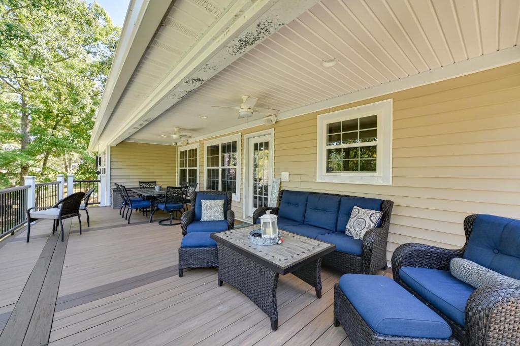 a porch with blue couches and a table and chairs at Lakefront Gilbertville Haven with Private Boat Dock! in Gilbertsville