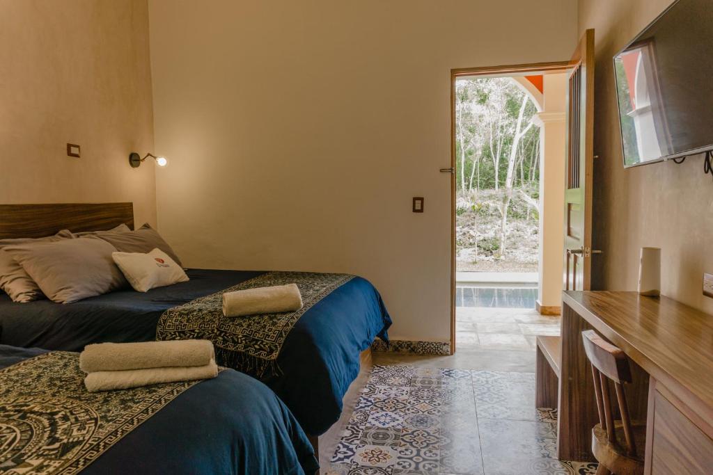a bedroom with two beds and a tv and a window at VILLA UNAHANA in Valladolid