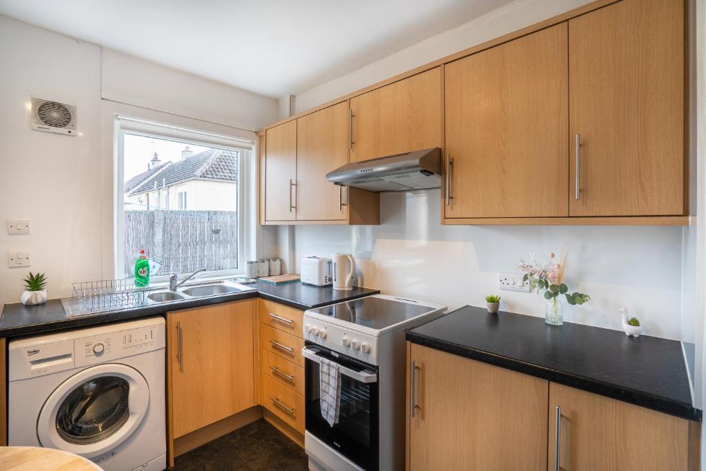 a kitchen with wooden cabinets and a sink and a dishwasher at 2 Bed Bungalow - Free Parking 
