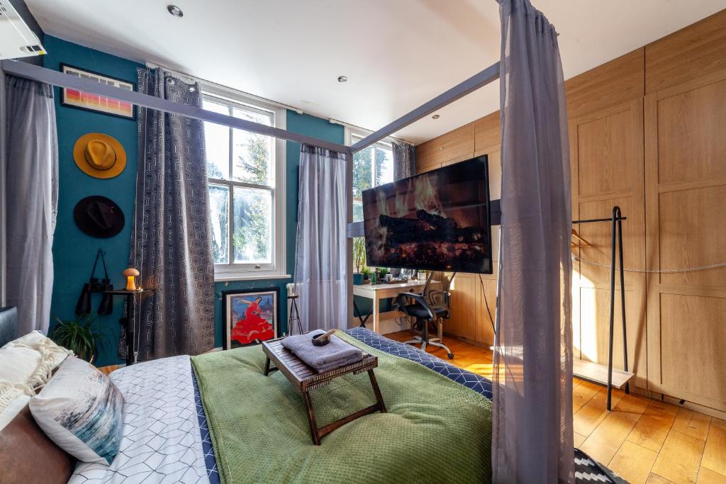 1 dormitorio con cama con dosel y TV en Master En - Suite Townhouse double with Garden & Hot Tub, en Londres