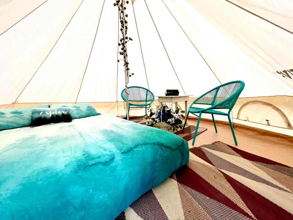 een slaapkamer in een tent met een bed en 2 stoelen bij M.Ruth Retreats in the Orchard 