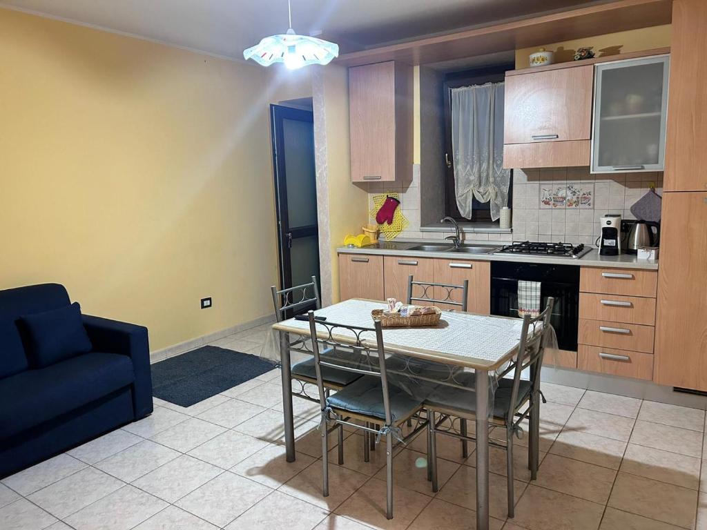cocina con mesa y sillas y sofá azul en Residence San Martino Appartamento mini en Busso