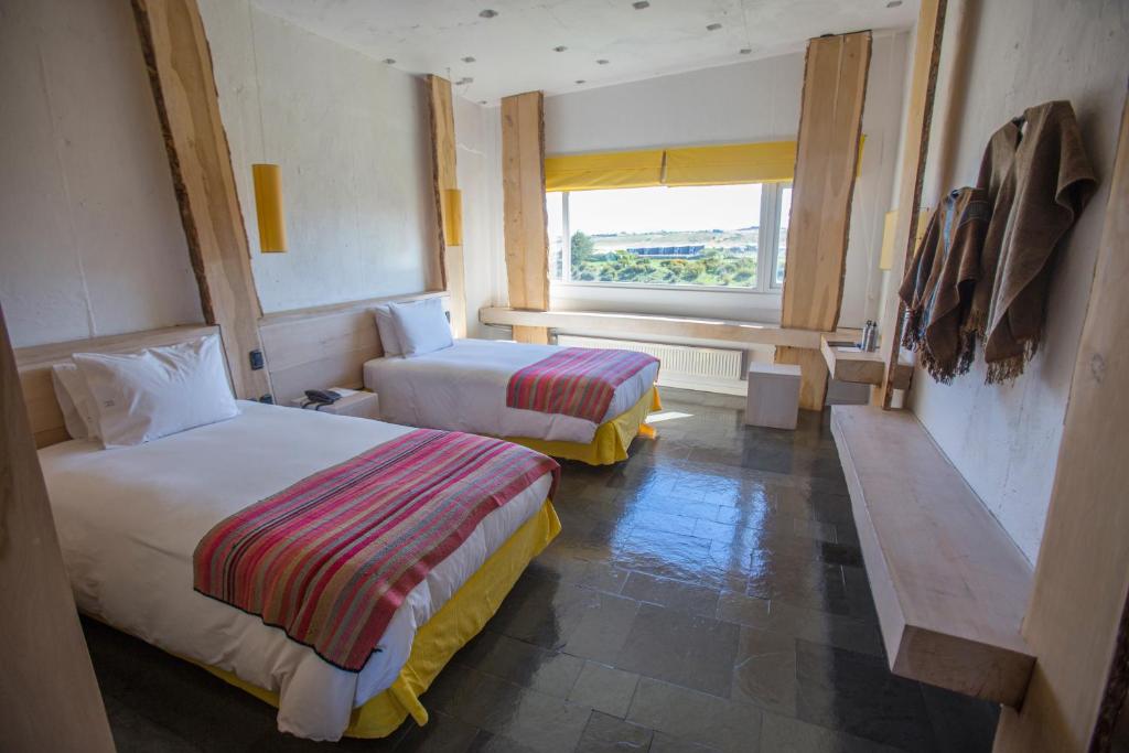a hotel room with two beds and a window at Remota Patagonia Lodge in Puerto Natales