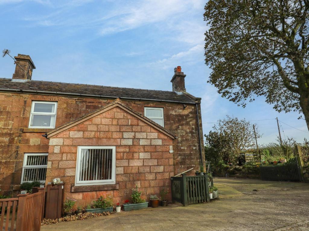 a brick house with a fence in front of it at The Granary in Biddulph