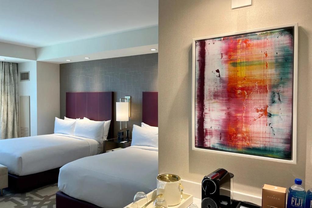 拉斯維加斯的住宿－Elegant Stay at Resorts World Strip Las Vegas，酒店客房设有两张床,墙上挂有绘画作品