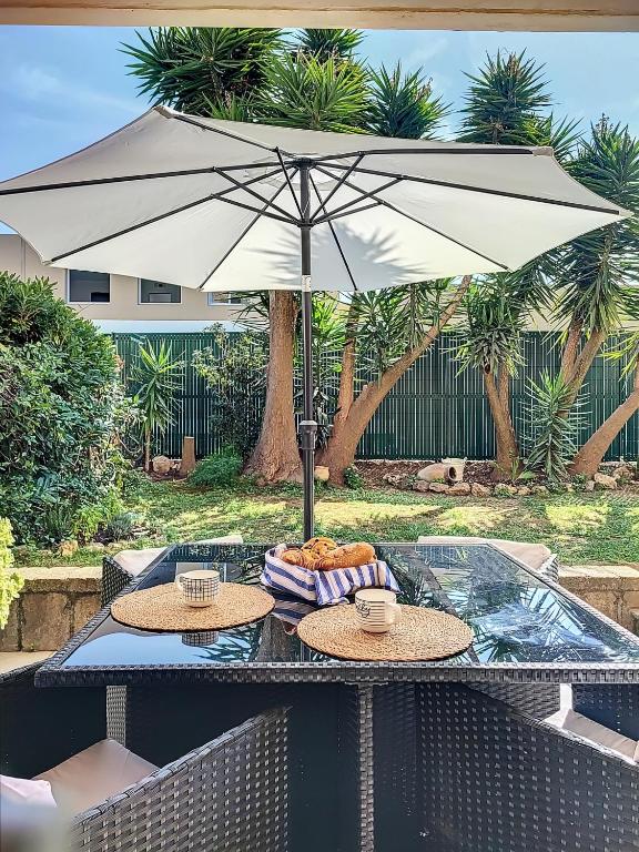 a table with an umbrella and two plates of food on it at Superbe appartement avec Jardin in Villeneuve-Loubet