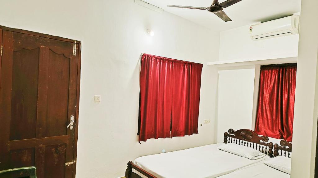 1 dormitorio con cama y cortina roja en Juliet's Homestay en Kochi