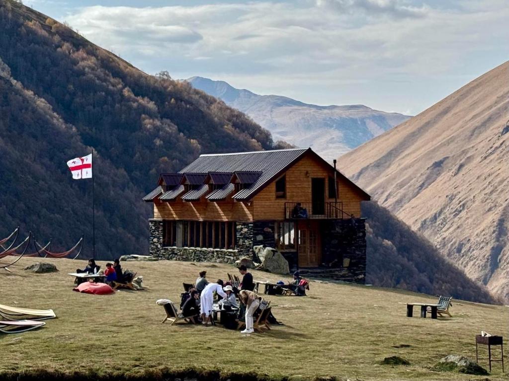 um grupo de pessoas sentadas em frente a uma cabana de madeira em Fifth Season em Juta