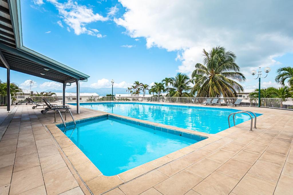 - une piscine d'eau bleue avec des palmiers dans l'établissement Studio élégant Marina du Gosier, à Pointe-à-Pitre