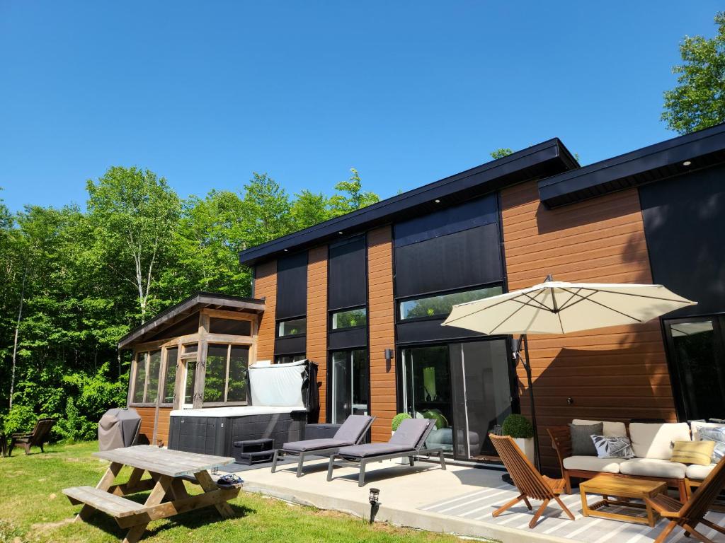 ein Haus mit einer Terrasse und einem Sonnenschirm in der Unterkunft Chalet Orkidea in Chertsey