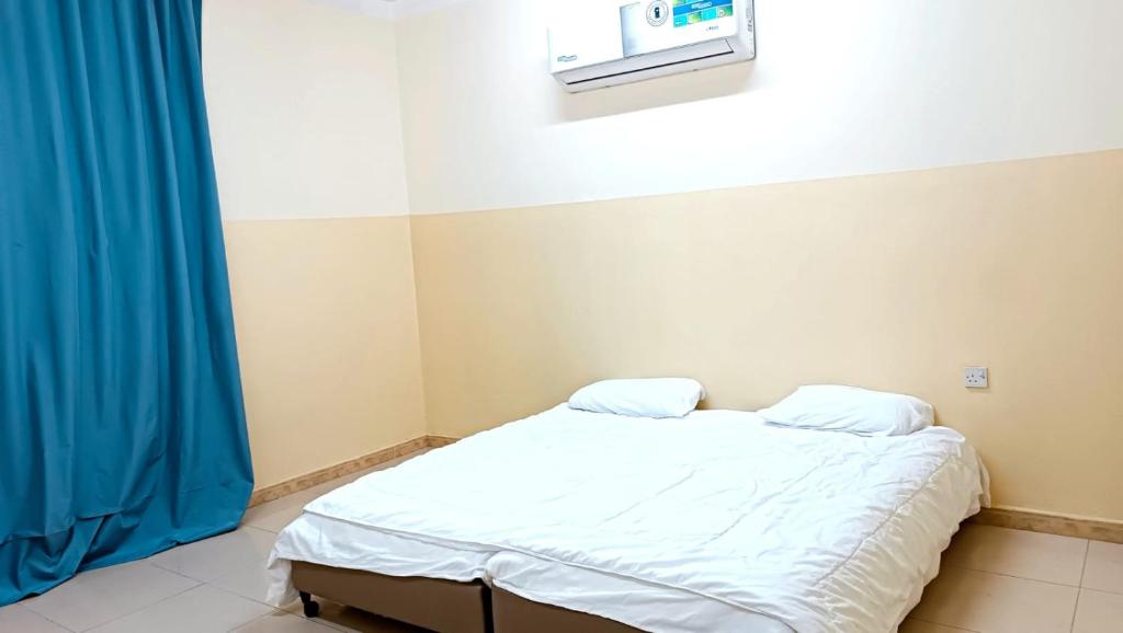 Pokój szpitalny z łóżkiem i niebieską zasłoną w obiekcie M&M للشقق الفندقية w mieście Majān