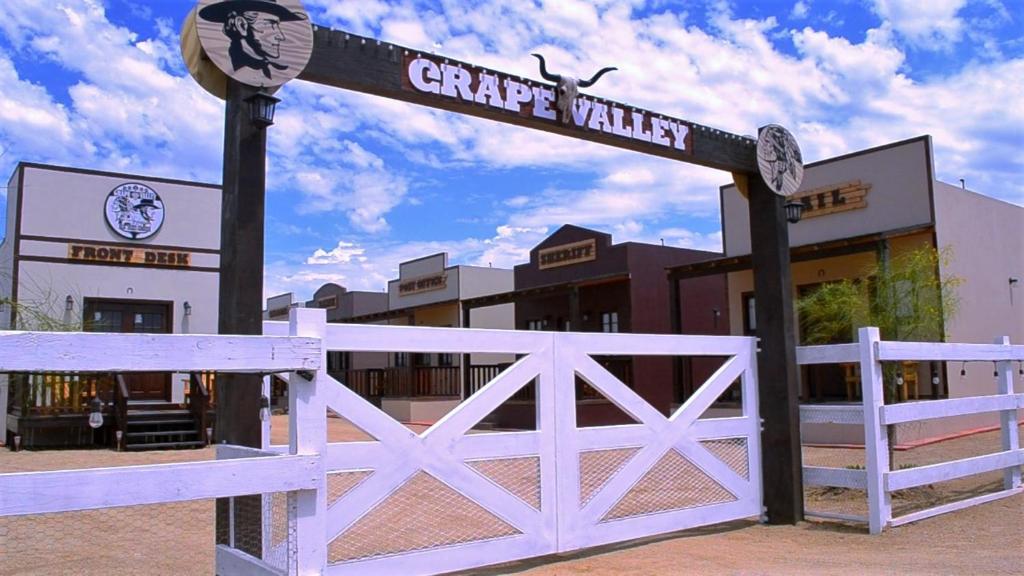 una señal frente a un edificio con una valla blanca en Grape Valley Old West Cabins, en Ensenada