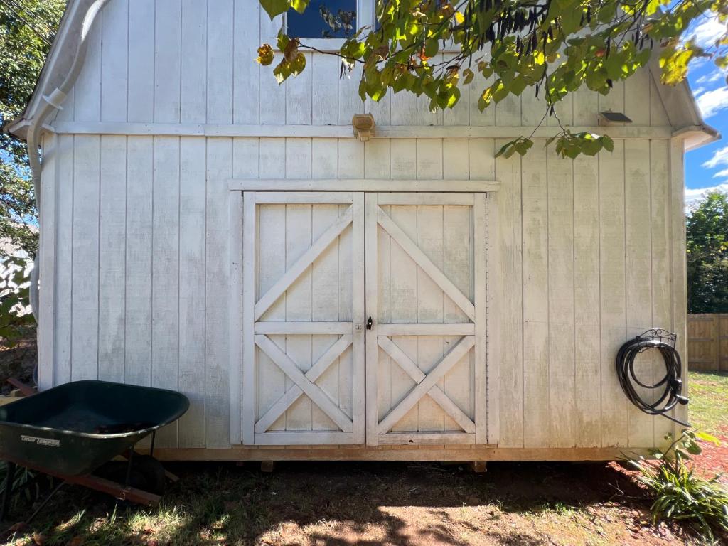 a wooden garage with a door and a wheelbarrow at 5BR 4B Huge Space with 2 Level Game Barn in Greenville