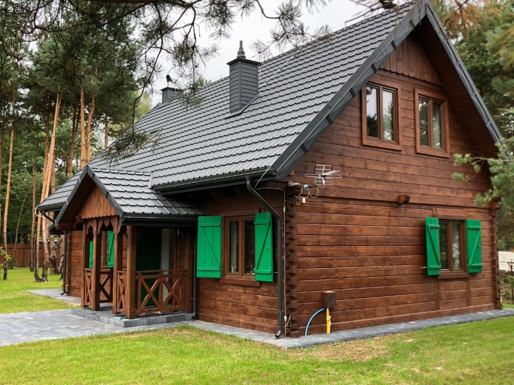 a log cabin with green windows and a roof at Zielono - domek na Roztoczu in AdamÃ³w