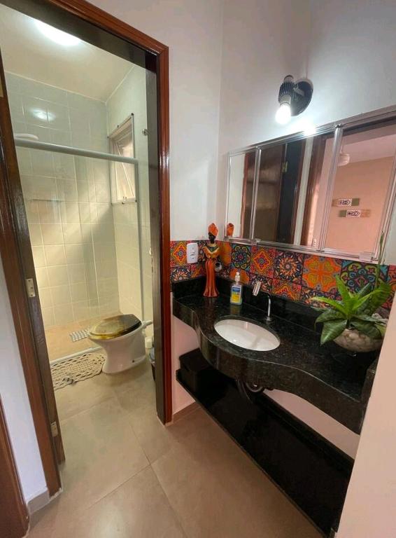 a bathroom with a sink and a toilet and a mirror at Praia Martin de Sá SP. in Caraguatatuba