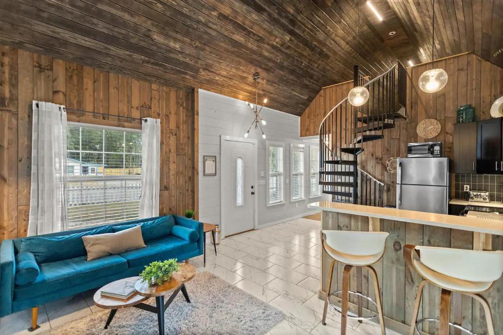 ein Wohnzimmer mit einem blauen Sofa und einer Küche in der Unterkunft Tiny Victorian built on TV show 2br 1 ba in Gainesville