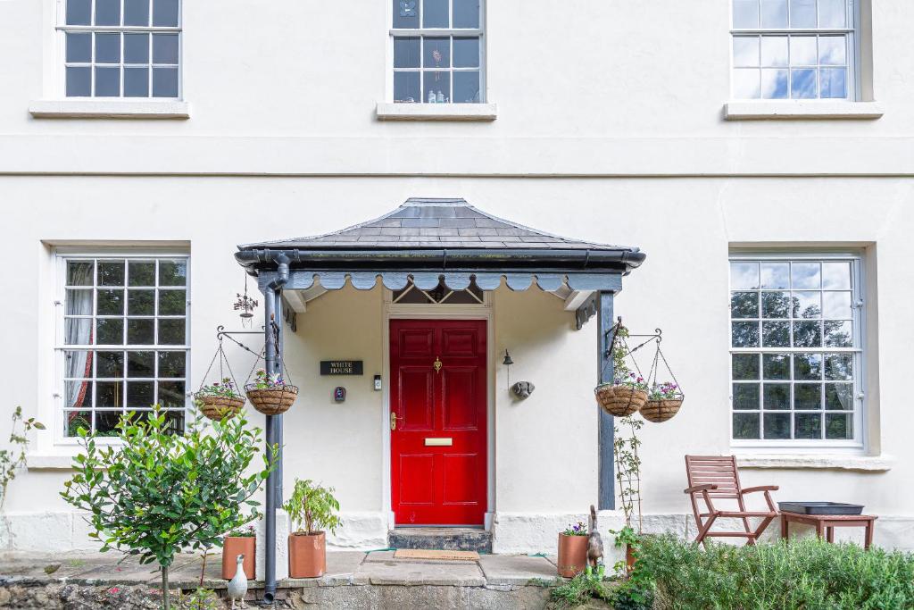a red door on a white house at Sophisticated & Secluded 3BD in Forest of Dean! in Lydbrook