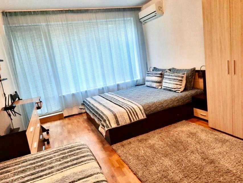 a bedroom with two beds and a window and two rugs at Cosy Breeze Apartment in Varna City