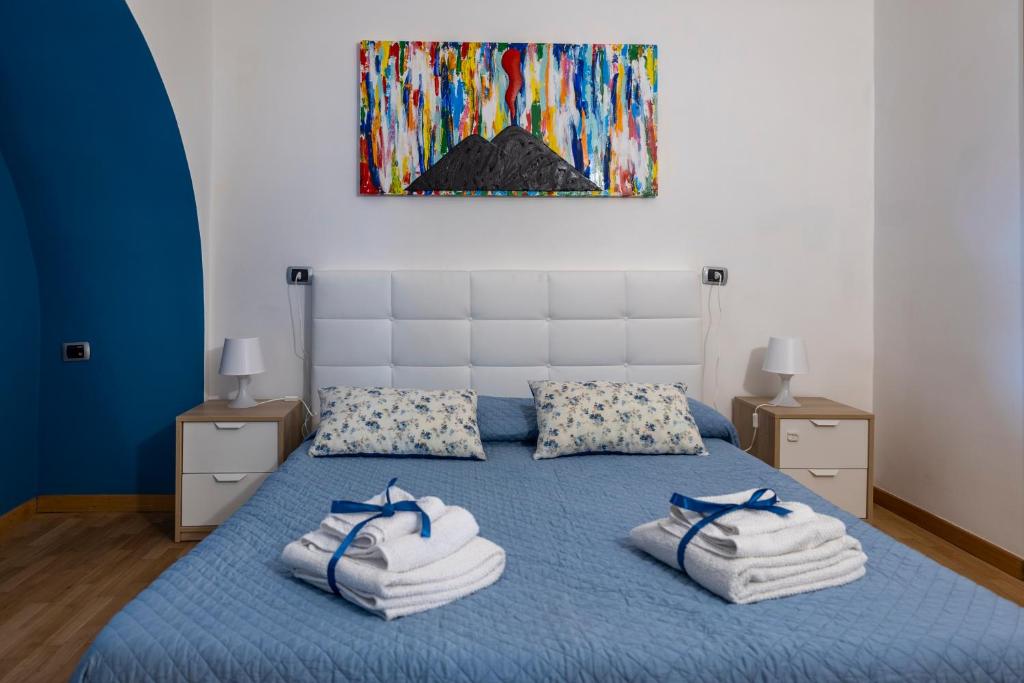 una camera da letto con un letto blu e asciugamani di Casa Adalù a Napoli