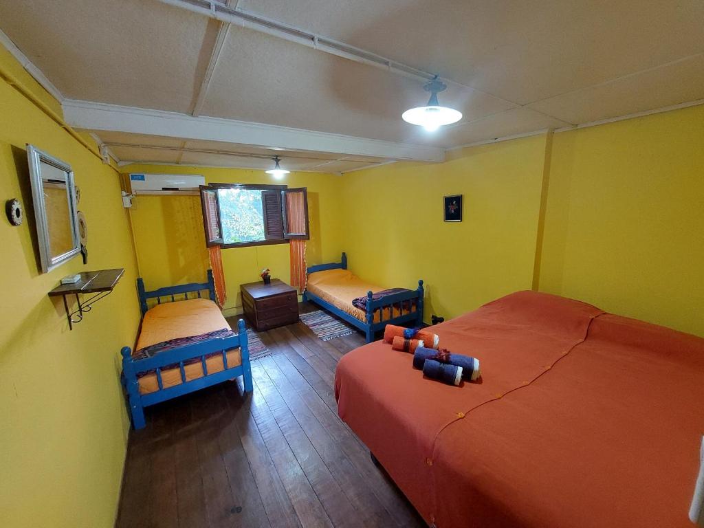 Habitación con 2 camas y paredes amarillas. en Posada de la Rosarito en Brandsen
