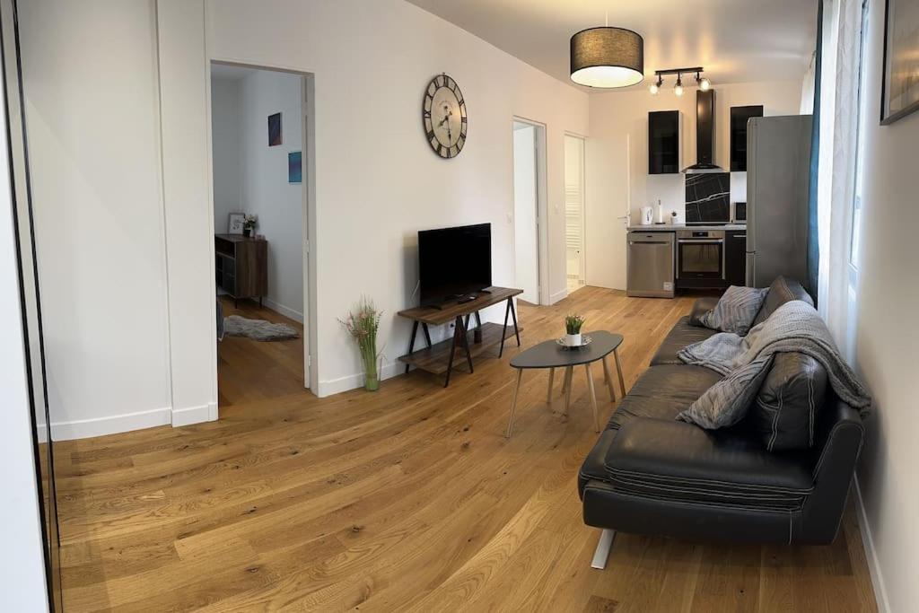 uma sala de estar com um sofá preto e uma mesa em Maison avec jardin em Viry-Châtillon