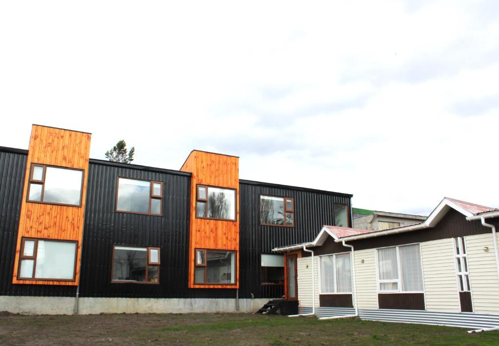 una fila de casas con fachada negra y naranja en Hostal Alamo Patagonico, en Puerto Natales