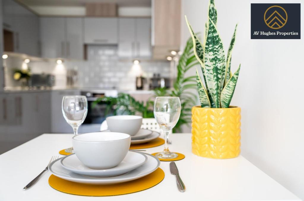 a table with plates and glasses and a vase with a plant at Luxurious One Bedroom Apartment by AV Hughes Properties Short Lets & Serviced Accommodation Milton Keynes with Fast Wi-Fi & Free Netflix in Milton Keynes