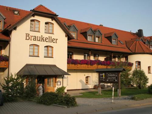 un grand bâtiment avec un panneau devant lui dans l'établissement Landgasthof - Braukeller - Fattigau, à Oberkotzau