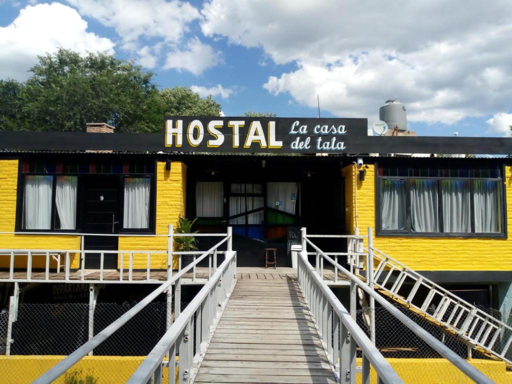 un edificio giallo con una passerella in legno di fronte di Hostel el Tata a Potrero de los Funes