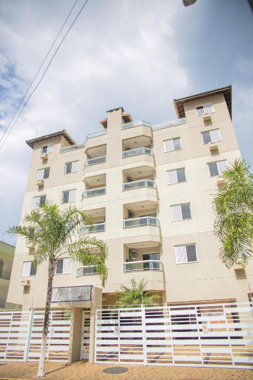 an apartment building with palm trees in front of it at Paramar Praia Grande in Ubatuba