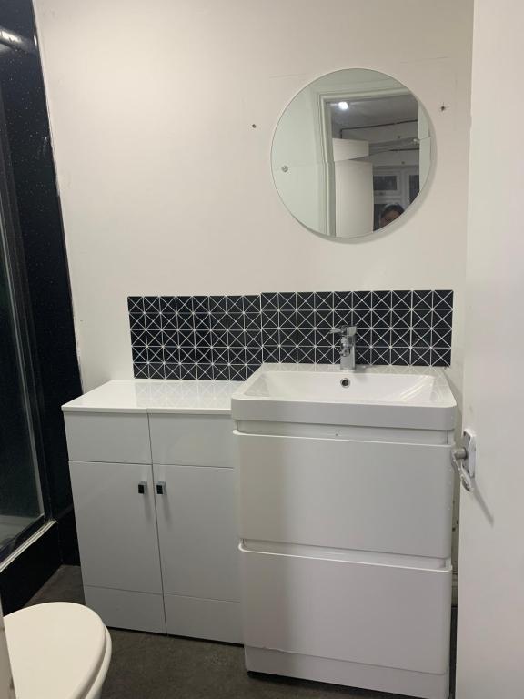 ein weißes Badezimmer mit einem Waschbecken und einem Spiegel in der Unterkunft Sam’s House in Purley
