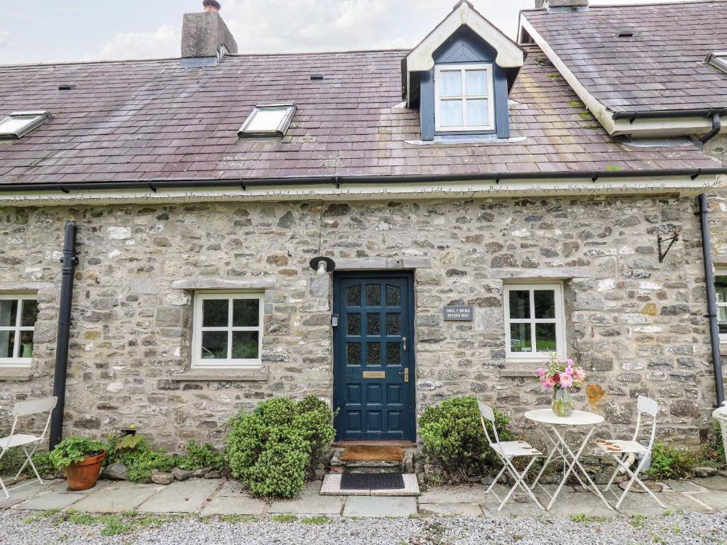 a stone house with a blue door and a table and chairs at Otters Holt in Llandeilo