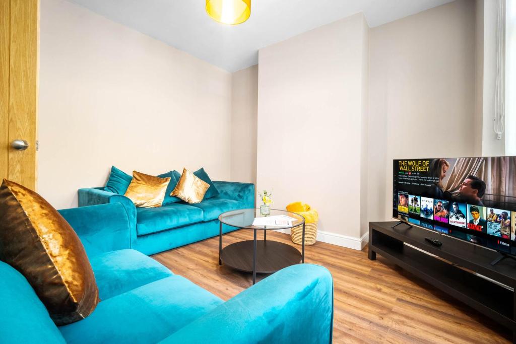 ein Wohnzimmer mit einem blauen Sofa und einem TV in der Unterkunft 3 bed house for Contractors & Families /Sleeps 5/Driveway parking 2 cars in Oldbury